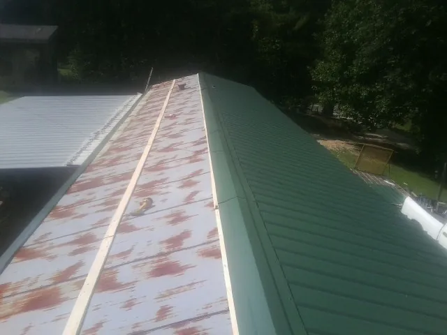 Old rusted panels beside newly installed green metal roofing — Wind Damage Roof Repair by Roofing Brothers in Pulaski